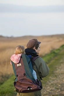 mother carrying toddler in backpack along coastal path North Norfolk winter mother carrying toddler in backpack along coastal path North Norfolk winter