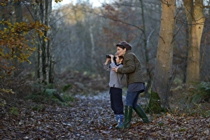 Mother showing son birds in woodland in autumn Norfolk