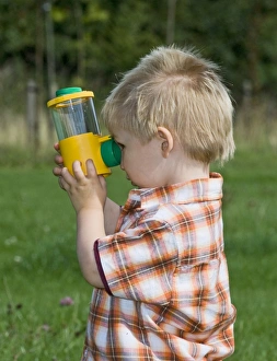 Toddler looking at insect in viewing tube Kent summer