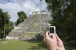 Tourist Prints: Tourist using a digital camera to photograph a Mayan temple at Yaxha nr Tikal Guatemala