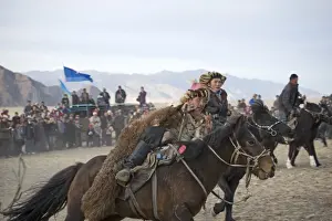 Mongolia Prints: The victor from a game of Kurbar (tug of war on horseback) gallops around arena