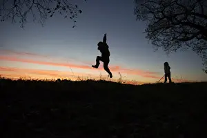 Children Prints: Young boy and girl playing at dusk on edge of woodland Norfolk winter
