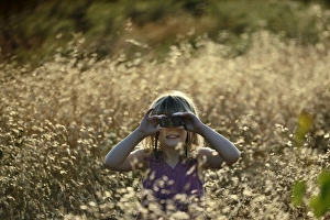 Young girl bird watching in meadow on a summer evening in Norfolk Young girl bird watching in meadow on a summer evening in Norfolk