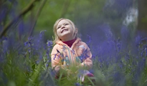 Child playing among Bluebells Norfolk May