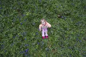 Child playing among Bluebells Norfolk May