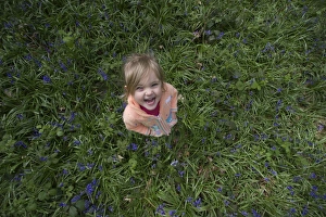 Child playing among Bluebells Norfolk May
