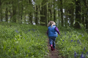 Trees Prints: Young girl running along woodland path Norfolk May